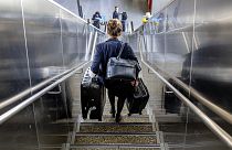 A woman carries her luggage down the stairs at the international airport in Frankfurt, 21 June 2022