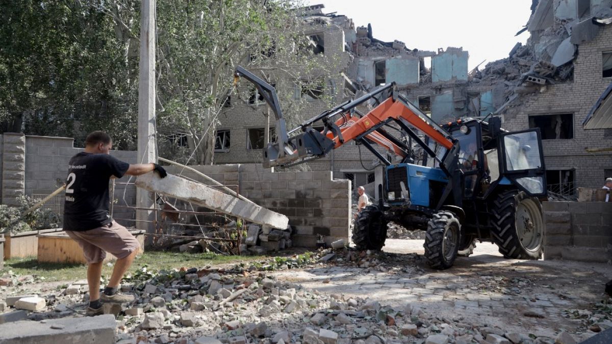 Коммунальные рабочие разбирают развалины студенческого общежития, разрушенного в результате обстрела в Николаеве, 2 августа 2022 года