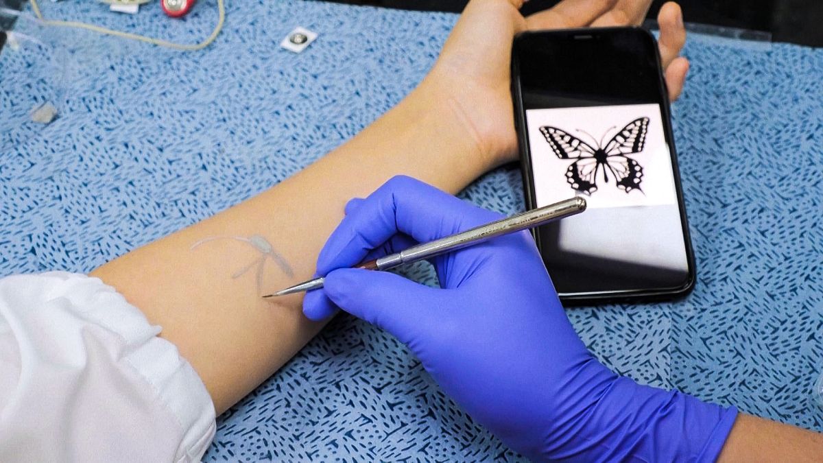 Image shows a researcher from the Korea Advanced Institute of Science and Technology applying a tattoo using 'electonic ink'.