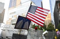 Bandeira dos EUA colocada juntamente com uma fotografia das Torres Gémeas em memorial das vítimas do 11 de setembro, Nova Iorque