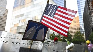 Bandeira dos EUA colocada juntamente com uma fotografia das Torres Gémeas em memorial das vítimas do 11 de setembro, Nova Iorque