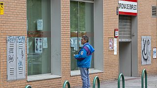 In this Tuesday, April 28, 2020 file photo, a man looks at notices on the window of an unemployment office in Madrid.
