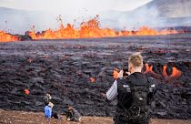 Touristes venus admirer la lave s'échappant d'une fissure volcanique près de Grindavík, dans l'ouest de l'Islande, le 3 août 2022