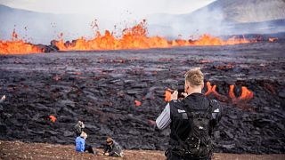 Touristes venus admirer la lave s'échappant d'une fissure volcanique près de Grindavík, dans l'ouest de l'Islande, le 3 août 2022