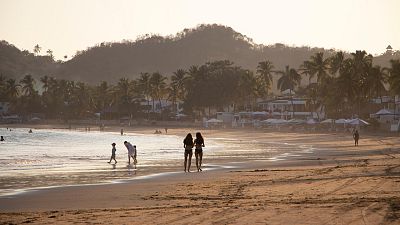 People walk on Manzanillo beach in Mexico.