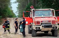 Des pompiers se tiennent à côté d'un camion de pompiers à La Teste-de-Buch, près d'Arcachon, dans le sud-ouest de la France, mardi 19 juillet 2022.