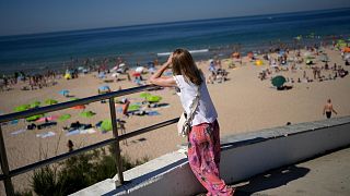 FILE - A woman looks down at Carcavelos beach, outside Lisbon, Friday, July 8, 2022.