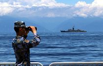 A People's Liberation Army member looks through binoculars during military exercises as Taiwan’s frigate Lan Yang is seen at the rear, on Friday, Aug. 5, 2022.