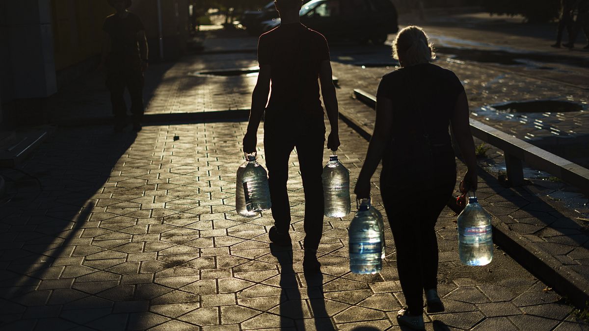 Egy házaspár vizes palackokat visz, miután feltöltötték őket egy boltban a kelet-ukrajnai Pokrovszkban, a donyecki régióban, 2022. augusztus 4-én. 