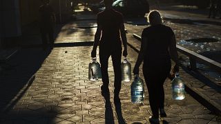 Egy házaspár vizes palackokat visz, miután feltöltötték őket egy boltban a kelet-ukrajnai Pokrovszkban, a donyecki régióban, 2022. augusztus 4-én.