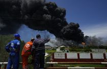 Workers of the Cuba Oil Union watch a huge rising plume of smoke from the Matanzas Supertanker Base, as firefighters work to quell a blaze  in Matazanas, Cuba, Aug. 6, 2022.
