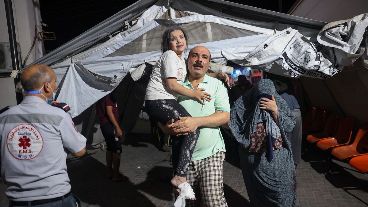 فلسطيني يحمل طفلة جريحة إلى مستشفى في رفح 