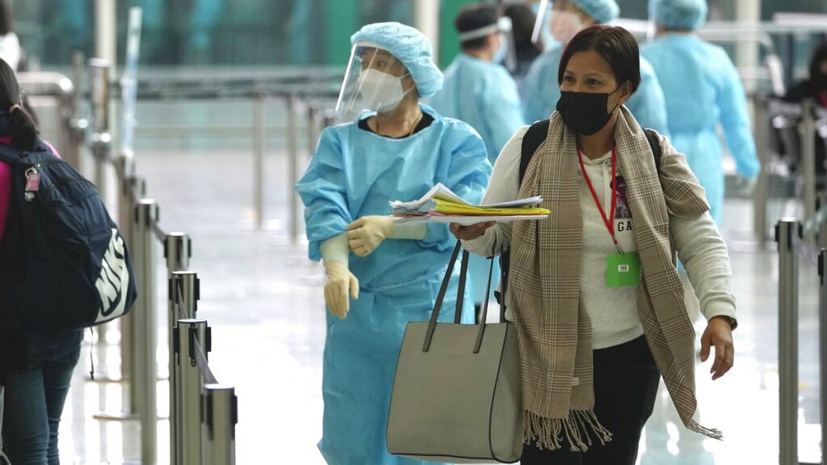 موظفون يوجهون الركاب القادمين مباشرة من مانيلا للحافلات إلى فنادق الحجر الصحي في مطار هونغ كونغ الدولي، الجمعة 1 أبريل 2022