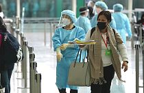 موظفون يوجهون الركاب القادمين مباشرة من مانيلا للحافلات إلى فنادق الحجر الصحي في مطار هونغ كونغ الدولي، الجمعة 1 أبريل 2022