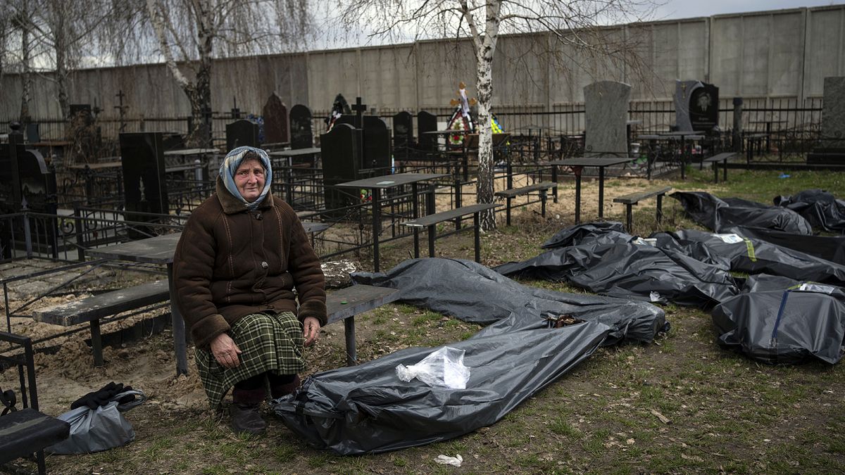 Nadiya Trubchaninova sits next to a plastic bag that contains the body of her son Vadym who was killed by Russian soldiers in Bucha