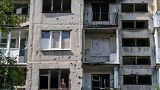Пожилая женщина выглядывает из окна своей квартиры в Славянске после ночного обстрела (7 августа 2022 г.)