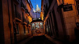 El tranvía número 28, uno de los favoritos de los turistas, circula por una estrecha calle del antiguo barrio lisboeta de Alfama al caer la noche.