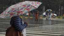 أشخاص يمشون تحت المطر حاملين مظلات في حيدر أباد، الهند