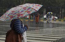 أشخاص يمشون تحت المطر حاملين مظلات في حيدر أباد، الهند