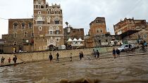 الناس في شارع غمرته المياه بعد هطول أمطار غزيرة في العاصمة اليمنية صنعاء> 2022/08/09