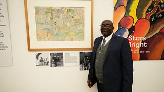 Gift Livingtsone Sango, 65, stands next to a painting by his father depicting Jesus as a Black man at the National Gallery of Zimbabwe
