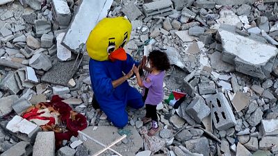 Un clown avec une enfant au milieu des décombres, à Rafah, dans les territoires palestiniens, 09/08/2022