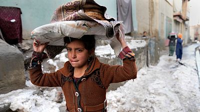 A girl carries breads on her head as she walks in the snow, in Kabul, Afghanistan, Tuesday, Feb. 8, 2022.