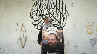 الفلسطينية دلال عواودة تحمل صورة لزوجها المعتقل في السجون الإسرائيلية والمضرب عن الطعام احتجاجاً على اعتقاله إدارياً، 11 أغسطس 2022.