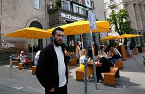 FILE - People, some of them still in masks to protect against coronavirus, enjoy outdoor McDonald's meal in downtown Kyiv, Ukraine, on June 9, 2020.