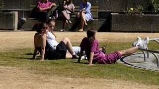 Hospital staff in London enjoy their lunch break on a small green grass patch, Thursday, Aug. 11, 2022.