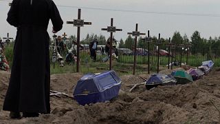 Die Särge mit den sterblichen Überresten unidentifzierter Leichen werden in Butscha, Ukraine, beigesetzt