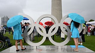 Hostessen und Besucher stehen neben den Olympischen Ringen anlässlich des 50. Jahrestages der Olympischen Sommerspiele 1972 in München