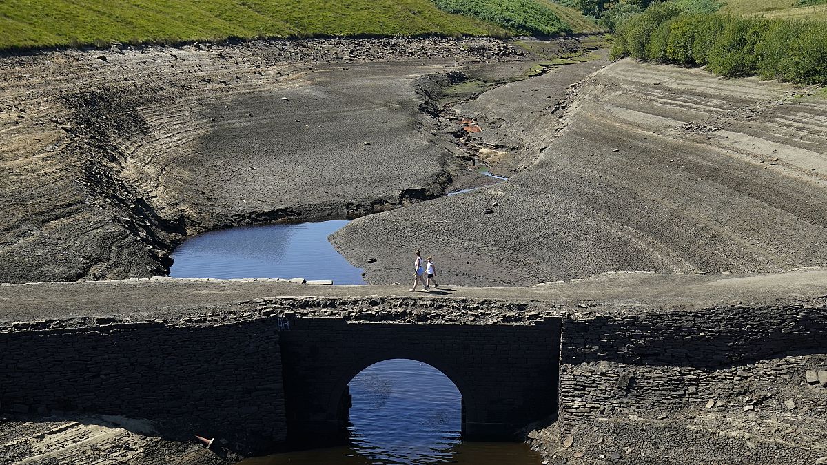 People walk across the dry cracked earth at Baitings Reservoir in Ripponden, West Yorkshire, Britain, Friday August 12, 2022. 