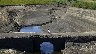 People walk across the dry cracked earth at Baitings Reservoir in Ripponden, West Yorkshire, Britain, Friday August 12, 2022. 