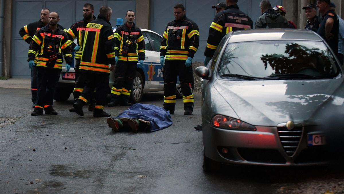 Tűzoltók állnak egy holttest mellett a támadás helyszínén a montenegrói Podgoricától mintegy 30 kilométerre nyugatra fekvő Cetinjében 2022. augusztus 12-én, pénteken.