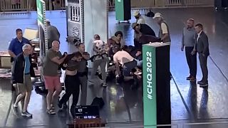 Standbild aus einem Video, das zeigt, wie ein Mann von der Bühne eskortiert wird, während sich Menschen um den Autor Salman Rushdie kümmern.