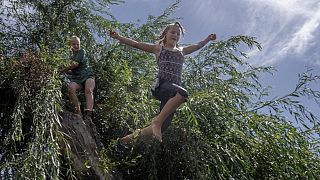 Ukrainian girl Dasha (R) jumps into a lake as Sasha waits behind in the eastern Ukrainian Donbas region, on 8 August, 2022.