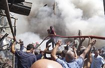 People help firefighters to deliver water to extinguish flames at Surmalu market about two kilometers (1.2 miles) south of the center Yerevan, Armenia, Sunday, Aug. 14, 2022.