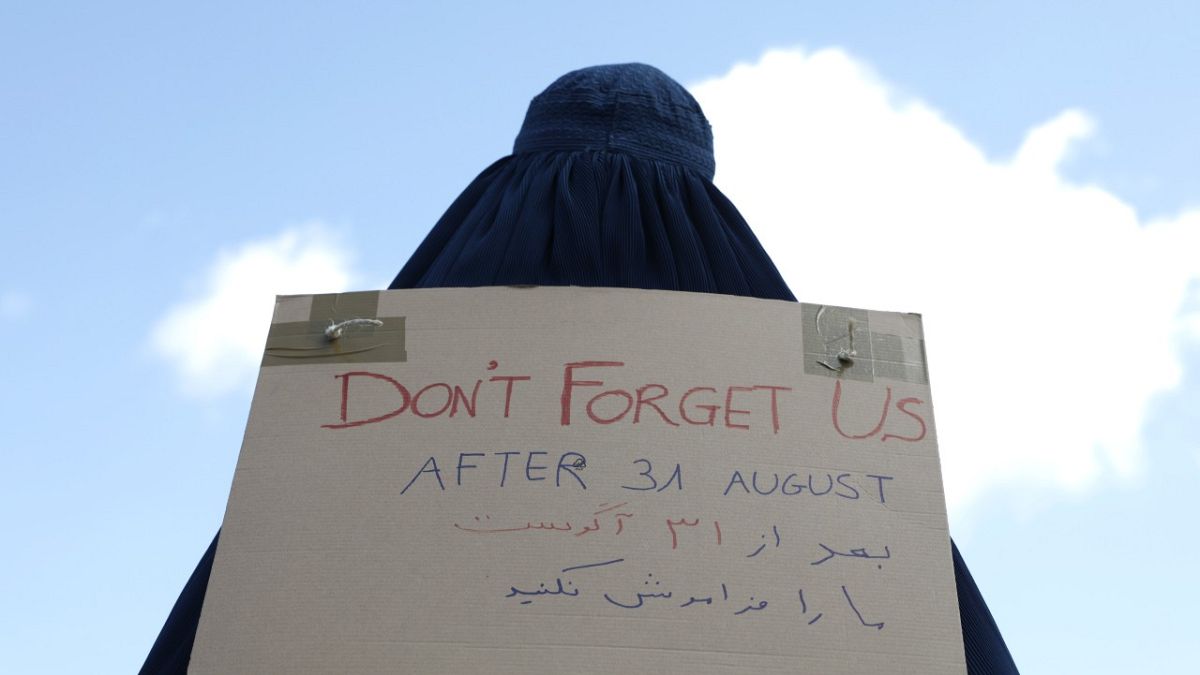 سيدة أفغانية ترتدي البرقع وتحمل لافتة مكتوب عليها لا تنسونا أمام السفارة الفرنسية في كابول، أفغانستان.   