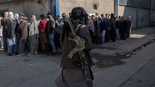صف دریافت پول از خودپرداز در کابل و یک مامور طالبان که بر اوضاع نظارت دارد