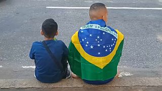 Brasileños sentados en la calle con una bandera en la espalda