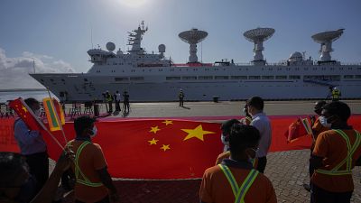 Les employés du port d'Hambantota tendent un gigantesque drapeau chinois sur les quais pour accueillir le navire chinois Yuan Wang 5 le 16 août 2022.