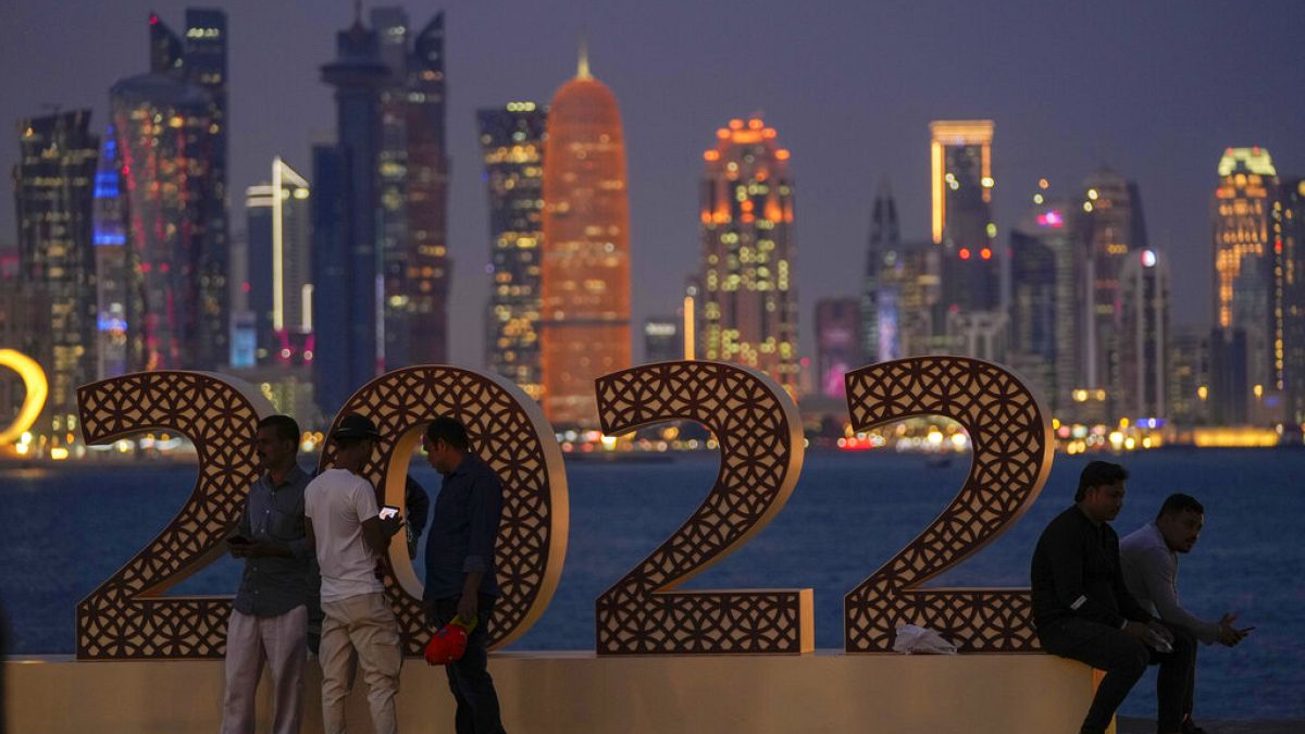 A katari vébére érkező turisták pózolnak a felhőkarcolok előtt Dohában
