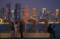 A katari vébére érkező turisták pózolnak a felhőkarcolok előtt Dohában