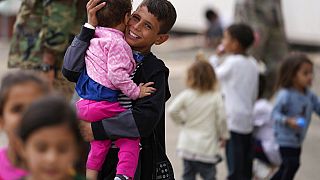 Ein evakuierter afghanischer Junge mit einem Kind auf dem Arm, auf dem US-Luftwaffenstützpunkt Ramstein, 24. August 2021