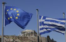 The Greek, right, and the European flags wave under the ancient Acropolis hill in Athens, July 2015.