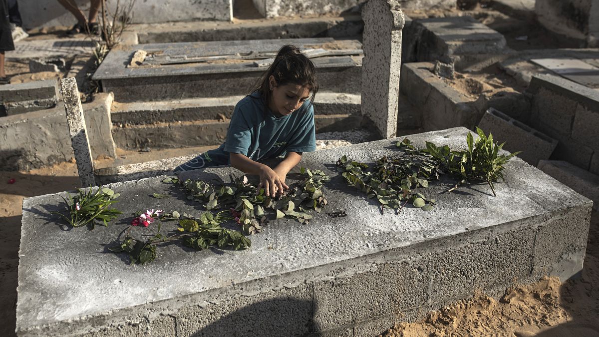 فتاة فلسطينية تضع الورود على قبر أحد أبناء عائلة نجم في مقبرة الفالوجة بجباليا شمال قطاع غزة، الثلاثاء 16 أغسطس 2022. 
