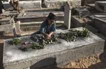 فتاة فلسطينية تضع الورود على قبر أحد أبناء عائلة نجم في مقبرة الفالوجة بجباليا شمال قطاع غزة، الثلاثاء 16 أغسطس 2022. 
