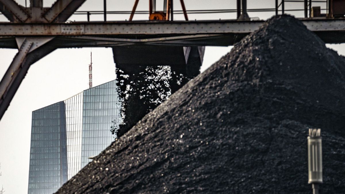 An excavator unloads coal from a barge onto a stockpile next to a power plant, while the ECB building can be seen in the background in Frankfurt, Germany, Jan. 3, 2022.