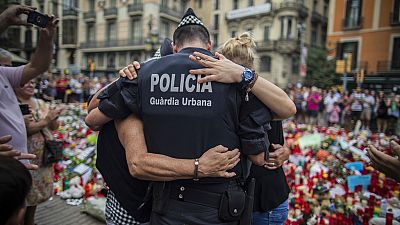 Photo d'archive du 21 aout 2017, quatre jours après l'attaque à Barcelone, un policier serre des personnes dans ses bras